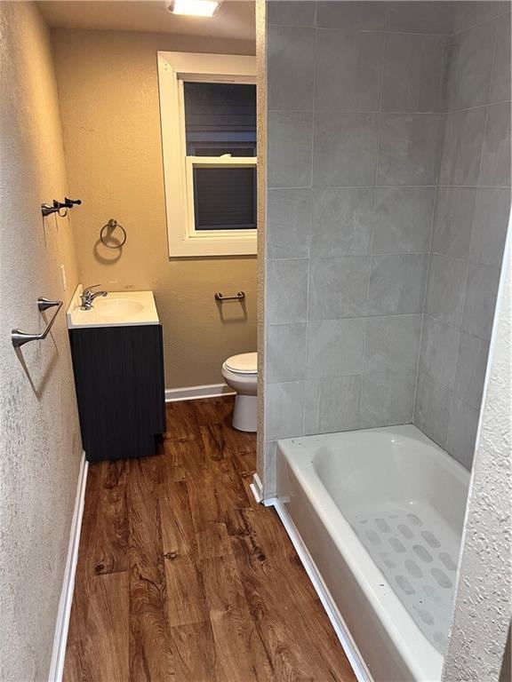 full bath featuring toilet, vanity, baseboards, and wood finished floors