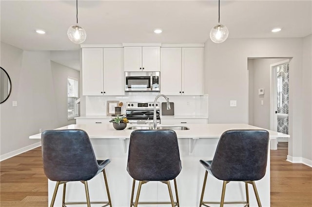 kitchen featuring a sink, light wood-type flooring, backsplash, and stainless steel appliances