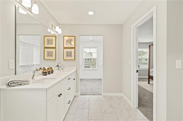 ensuite bathroom with plenty of natural light, marble finish floor, and a sink