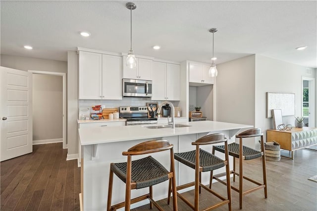 kitchen featuring dark wood-type flooring, backsplash, appliances with stainless steel finishes, and light countertops