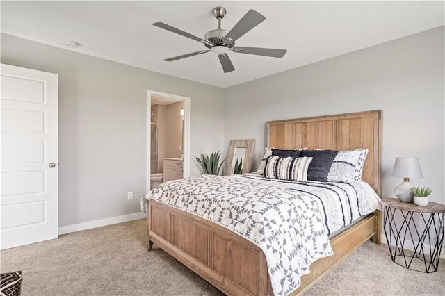 bedroom featuring light colored carpet, ensuite bath, baseboards, and ceiling fan