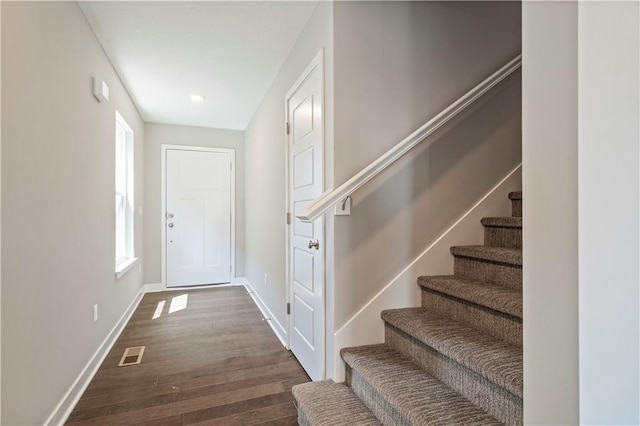 doorway featuring stairway, baseboards, dark wood-type flooring, and visible vents