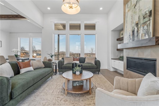 living area featuring recessed lighting, wood finished floors, baseboards, and a tile fireplace