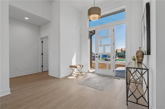 entryway featuring french doors, baseboards, a high ceiling, and wood finished floors