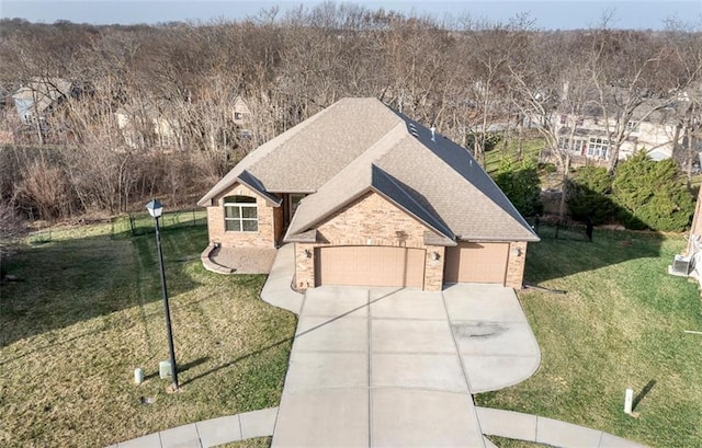 view of front of property with brick siding, a shingled roof, a front yard, a garage, and driveway