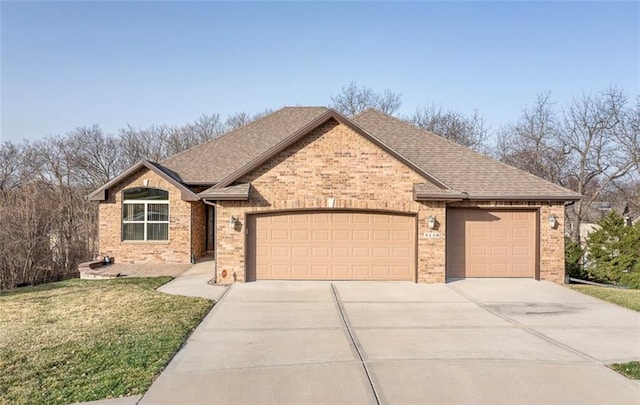 view of front of house featuring roof with shingles, an attached garage, concrete driveway, a front lawn, and brick siding