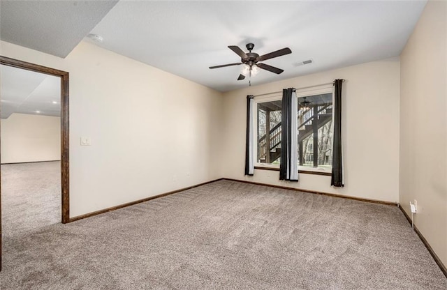 carpeted empty room featuring visible vents, baseboards, and ceiling fan