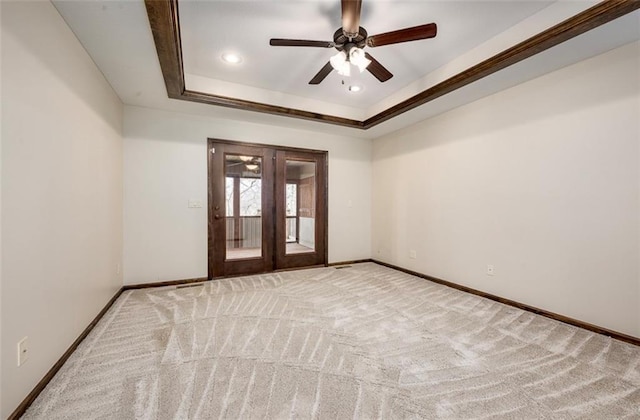 spare room featuring ceiling fan, baseboards, a tray ceiling, carpet floors, and french doors