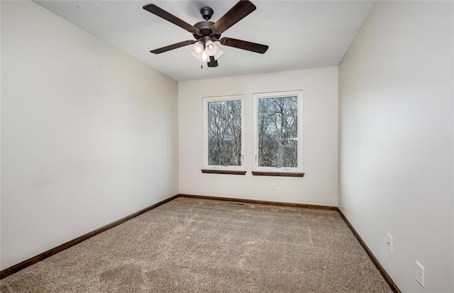 carpeted empty room featuring a ceiling fan and baseboards