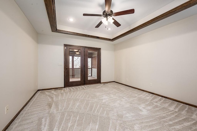 unfurnished room featuring baseboards, carpet flooring, french doors, a raised ceiling, and a ceiling fan