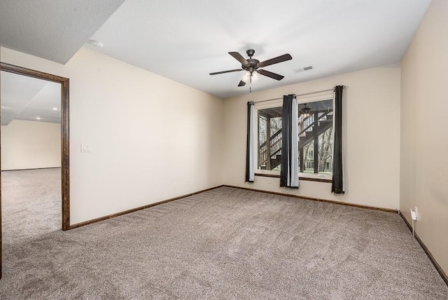 carpeted spare room featuring visible vents, baseboards, and ceiling fan