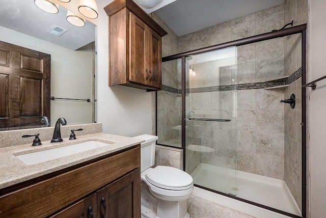 bathroom featuring visible vents, a shower stall, toilet, and vanity