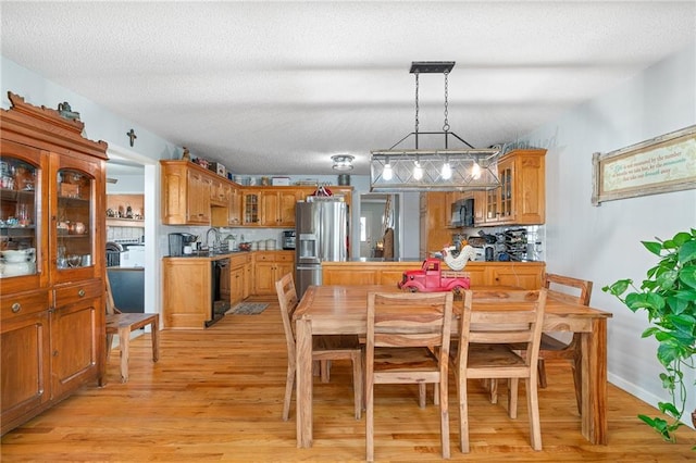 dining area with a textured ceiling, light wood-type flooring, and baseboards