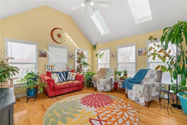 living area featuring ceiling fan, wood finished floors, high vaulted ceiling, and a skylight