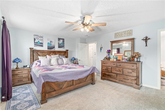 bedroom with a textured ceiling, ensuite bath, carpet, baseboards, and ceiling fan