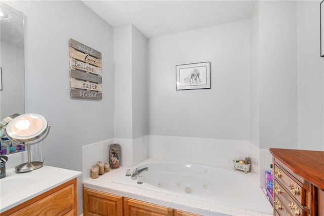 full bathroom with vanity, a tub with jets, and a textured ceiling