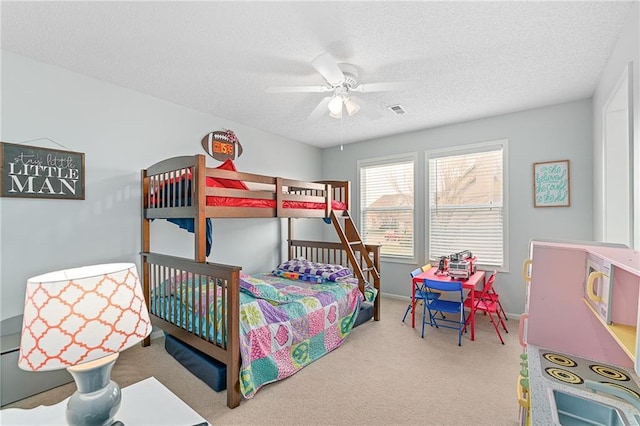 bedroom featuring a ceiling fan, visible vents, carpet floors, and a textured ceiling