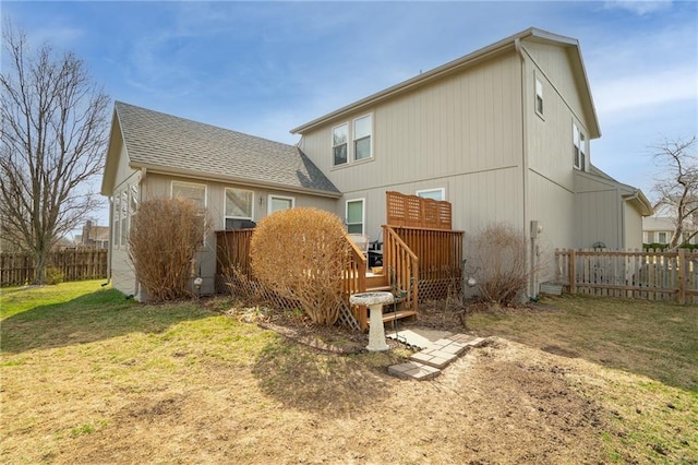 back of house featuring a yard, fence, and roof with shingles