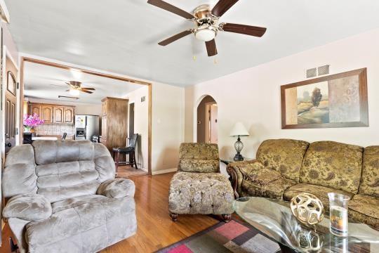 6745 Cleveland Ave, Kansas City, MO 64132 - living room featuring arched walkways, ceiling fan, visible vents, and light wood-style floors