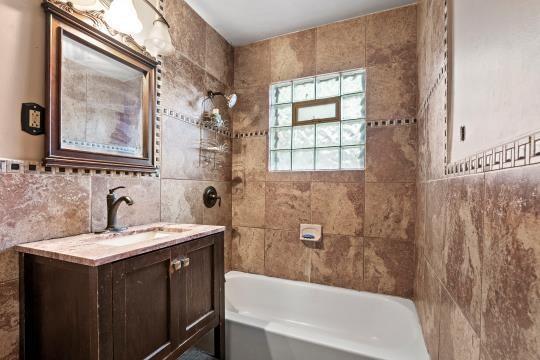 6745 Cleveland Ave, Kansas City, MO 64132 - full bath with vanity, shower / washtub combination, and tile walls