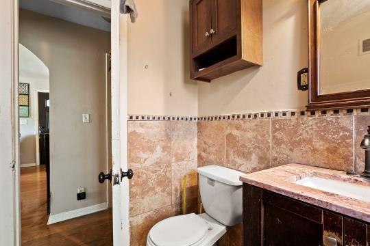 6745 Cleveland Ave, Kansas City, MO 64132 - bathroom with tile walls, wainscoting, wood finished floors, vanity, and toilet