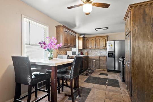 6745 Cleveland Ave, Kansas City, MO 64132 - kitchen featuring light tile patterned flooring, ceiling fan, tasteful backsplash, stainless steel fridge with ice dispenser, and white microwave