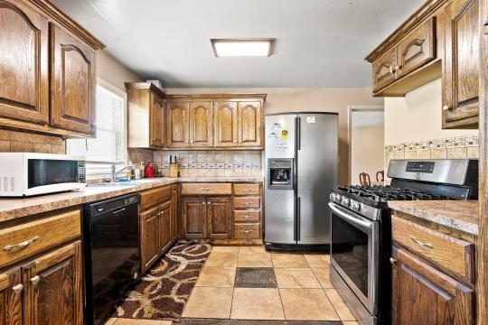 6745 Cleveland Ave, Kansas City, MO 64132 - kitchen featuring light tile patterned floors, appliances with stainless steel finishes, and backsplash