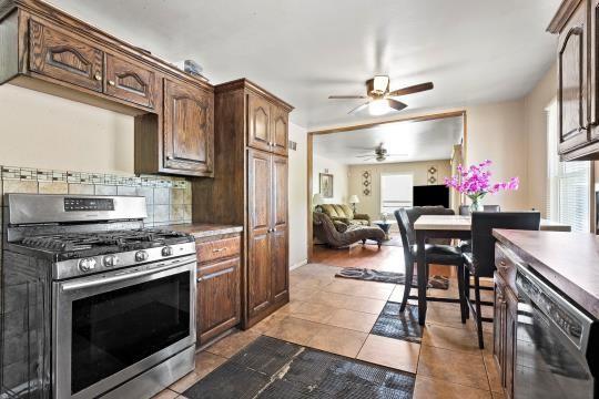 6745 Cleveland Ave, Kansas City, MO 64132 - kitchen featuring open floor plan, dark tile patterned flooring, a ceiling fan, appliances with stainless steel finishes, and backsplash
