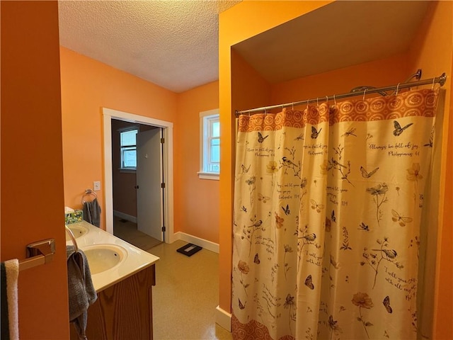 full bath with vanity, a shower with curtain, baseboards, and a textured ceiling