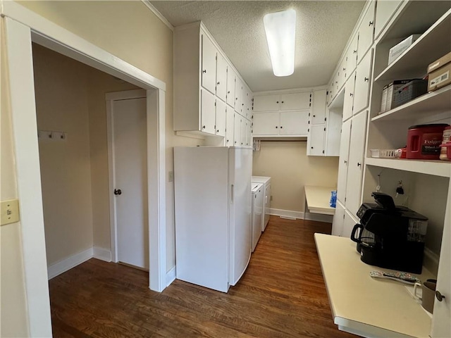 kitchen featuring dark wood-style floors, baseboards, freestanding refrigerator, a textured ceiling, and washer and clothes dryer