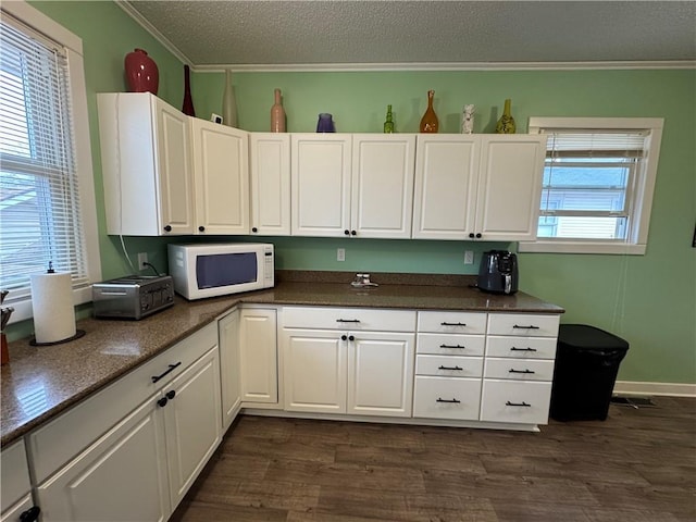 kitchen featuring dark countertops, white microwave, and ornamental molding