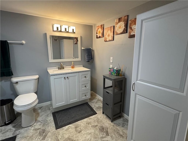 bathroom with baseboards, toilet, and vanity