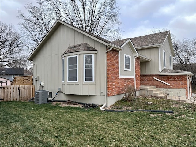 view of home's exterior featuring central AC, fence, a yard, board and batten siding, and brick siding