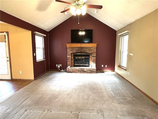 unfurnished living room with a healthy amount of sunlight, a fireplace, lofted ceiling, and ceiling fan