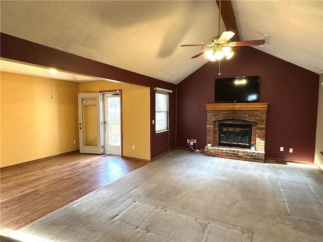 unfurnished living room with lofted ceiling with beams, a textured ceiling, ceiling fan, and a fireplace