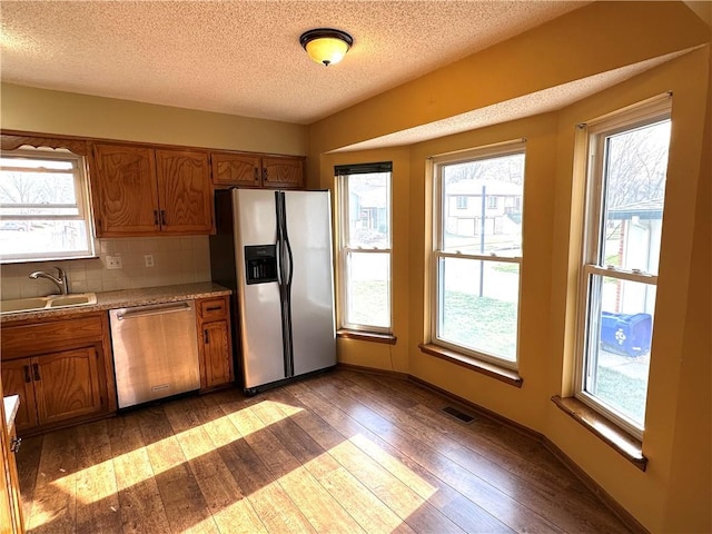 kitchen featuring a sink, stainless steel appliances, brown cabinets, and visible vents