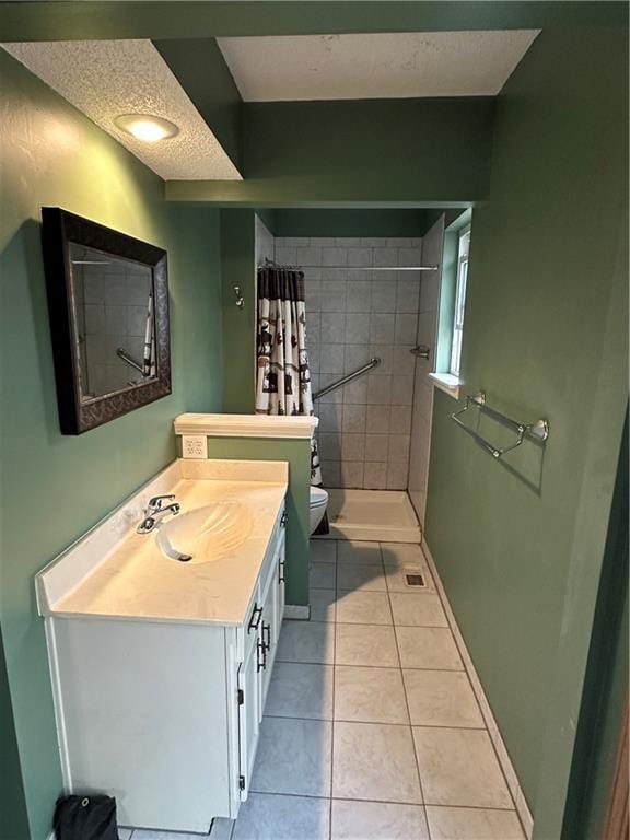 bathroom featuring vanity, baseboards, a tile shower, tile patterned floors, and toilet