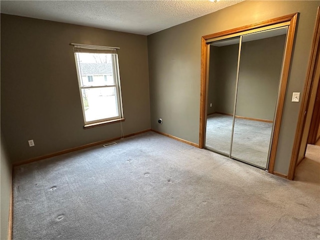 unfurnished bedroom with baseboards, visible vents, a closet, a textured ceiling, and carpet flooring