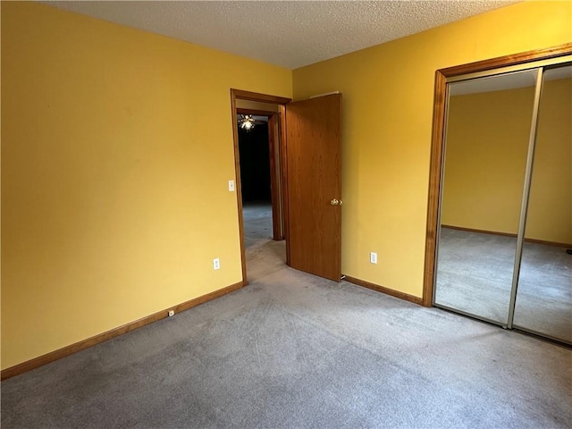 unfurnished bedroom with baseboards, a closet, carpet floors, and a textured ceiling