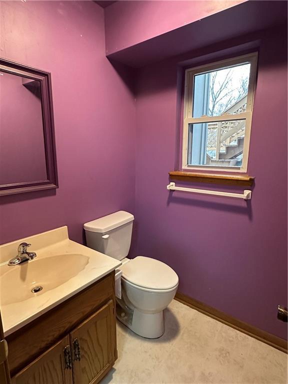 half bath with vanity, toilet, and baseboards