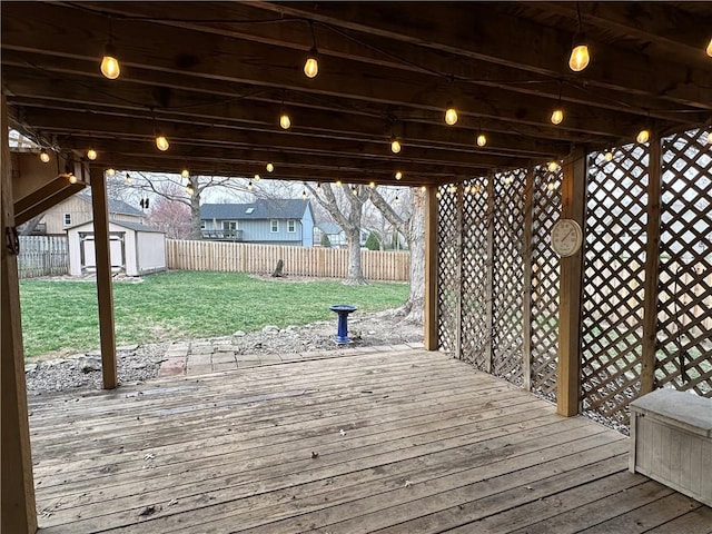 wooden terrace featuring a fenced backyard, a yard, a storage shed, and an outdoor structure