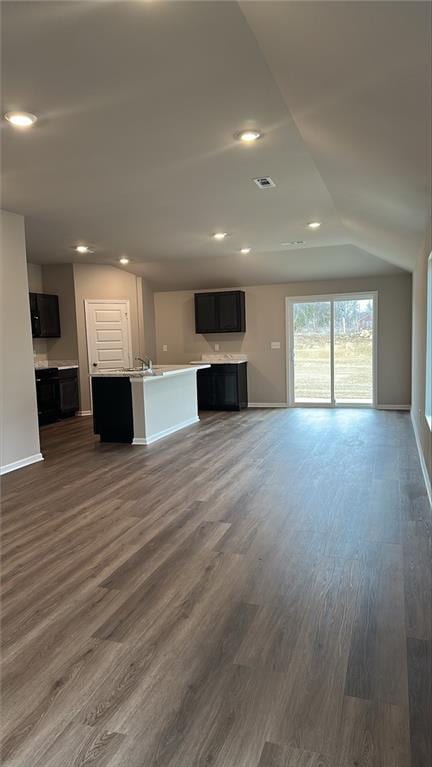 unfurnished living room with dark wood-style floors, recessed lighting, baseboards, and lofted ceiling