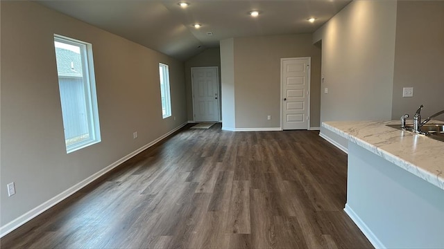 unfurnished living room with dark wood-type flooring, plenty of natural light, baseboards, and a sink