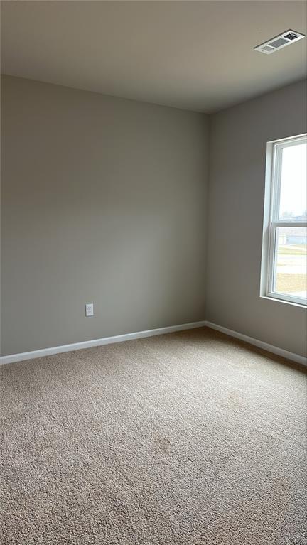 carpeted spare room featuring baseboards and visible vents