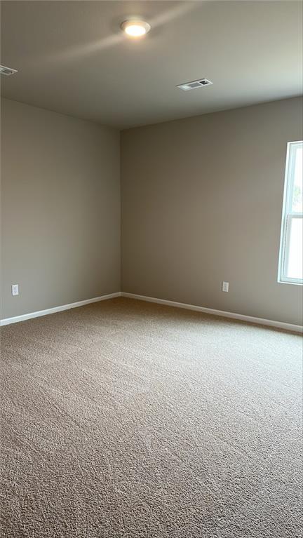 carpeted spare room featuring visible vents and baseboards