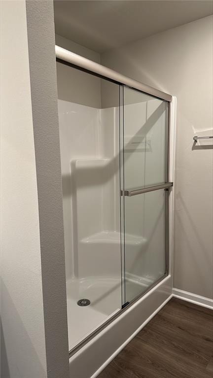 bathroom featuring a shower with shower door, baseboards, and wood finished floors