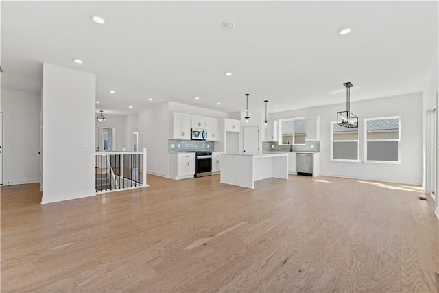 10612 N Jefferson St, Kansas City, MO 64155 - unfurnished living room featuring an inviting chandelier, recessed lighting, baseboards, and light wood finished floors