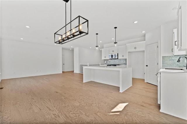 10612 N Jefferson St, Kansas City, MO 64155 - kitchen featuring stainless steel microwave, white cabinetry, decorative backsplash, and a sink