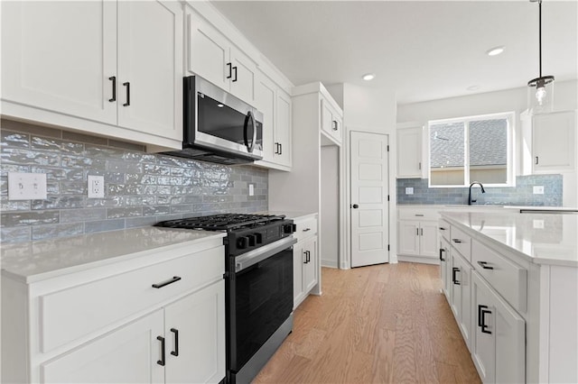 10612 N Jefferson St, Kansas City, MO 64155 - kitchen featuring light wood finished floors, stainless steel microwave, range with gas stovetop, white cabinetry, and light countertops