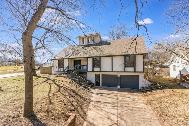tudor home featuring concrete driveway, stairway, an attached garage, and a porch